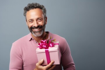 Canvas Print - Portrait of a satisfied man in his 40s holding a gift on pastel gray background
