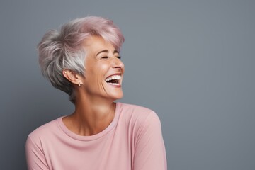Wall Mural - Portrait of a content woman in her 50s laughing isolated on pastel gray background