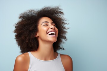 Wall Mural - Portrait of a joyful afro-american woman in her 20s laughing over pastel gray background