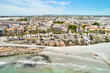 Aerial shot, drone point of view panoramic image of Torre de la Horadada townscape with sandy beach, turquoise bay and city rooftops at sunny summer day. Costa Blanca, Alicante, Spain