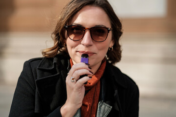 Close portrait of woman using e-cigarette outdoors.