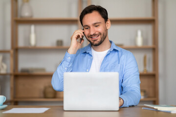 Aufkleber - A man is sitting in front of a laptop, engaged in a phone call. He appears focused as he communicates on the phone while working on his computer.