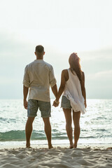 Wall Mural - Man and Woman Standing Holding Hands on the Beach