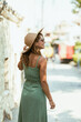 Woman in Green Dress and Hat Walking Down a Street