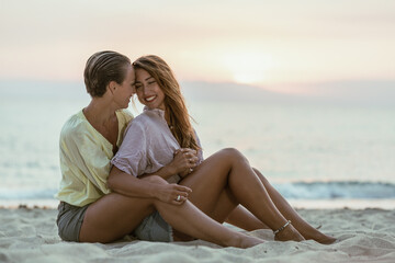 Canvas Print - Two Women Sitting in Hug on a Sandy Beach