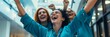 © gunzexx png and bg - A group of medical professionals in blue scrubs joyfully celebrate success with raised arms and cheers in a hospital hallway