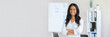© Prostock-studio - Portrait of happy African American businesswoman standing with crossed arms in front of her desk at modern office. Confident female entrepreneur looking at camera and smiling, copy space