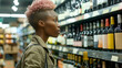 © Renata Hamuda - Young african woman with trendy short hair at the supermarket selecting a bottle of wine from the wine shelf