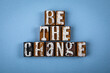 BE THE CHANGE. Wooden alphabet letter blocks on blue textured background