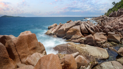 Poster - A rocky shoreline with a calm ocean in the background. The water is a deep blue color and the sky is a light blue color