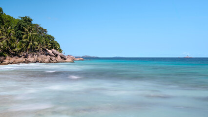 Poster - A beautiful blue ocean with a boat in the distance. The water is calm and the sky is clear, Seychelles Ladigue
