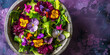 Green fresh mix salad with small flowers in a concrete bowl on a purple background. Top view.