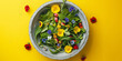 Green fresh mix salad with small flowers in a concrete bowl on a yellow background. Top view.