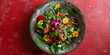 Green fresh mix salad with small flowers in a concrete bowl on a red background. Top view.