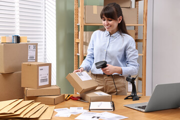 Poster - Parcel packing. Post office worker with scanner reading barcode at wooden table indoors