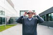 © Koldo_Studio - An elderly businessman adjusting his VR glasses outdoors, preparing to engage with the virtual environment.