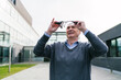 © Koldo_Studio - An elderly businessman inspecting his VR glasses outdoors, preparing to engage with a virtual environment.