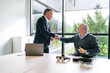 © Koldo_Studio - A businessman and client shake hands after finalizing a deal for VR glasses in a modern, bright office setting.