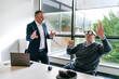 © Koldo_Studio - A client engages with a VR headset, reaching out with hands, while a businessman watches and discusses in an office setting.