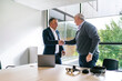 © Koldo_Studio - Two men, a businessman and a client, shake hands after a successful business deal on VR glasses in a modern office environment.