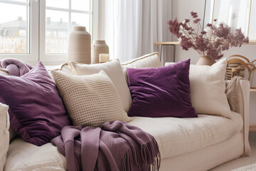 Wall Mural - Beige sofa with violet pillows and chunky knit plaid near window. Scandinavian hygge interior design of modern living room home.