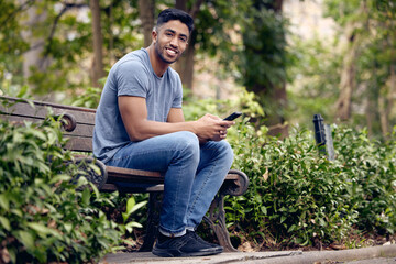 Poster - Phone, man and student in park, smile and typing in app with connection to social media and chat. University, education and person in campus with mobile, texting and check for update in studying
