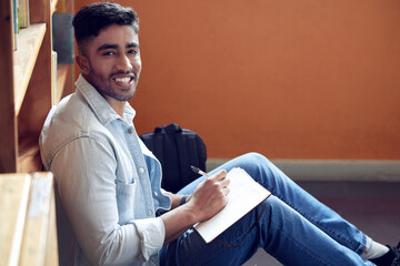 Poster - Male student, portrait and smile in library for study in university with notebook for education with writing. Scholarship, academic and research for knowledge on campus for doctorate in London.