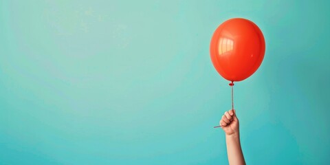 One red balloon floating up in the air held by a child's hand