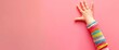 child hand reaching up against a plain pink wall, displaying a sense of effort and determination