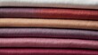 Close-up View of Stacked Colorful Textured Fabric in Shades of White, Red, and Purple.