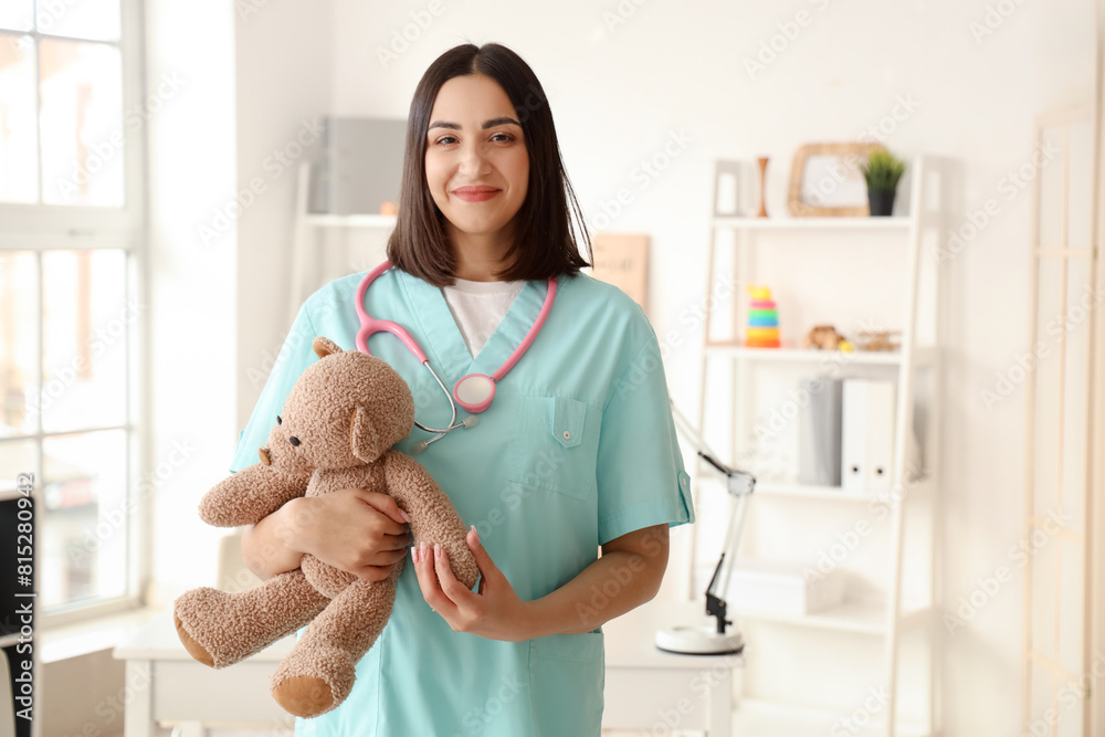 Female pediatrician with toy bear in clinic