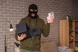 © Pixel-Shot - Male thief with open safe and money in room at night