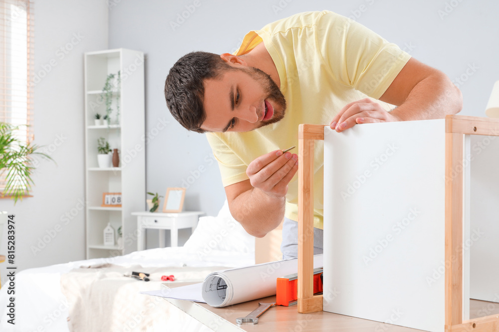 Young man assembling shelving unit in bedroom