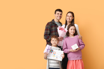 Sticker - Happy father and children greeting their mother with Mothers Day with bouquet of flowers, drawing and gift near orange wall