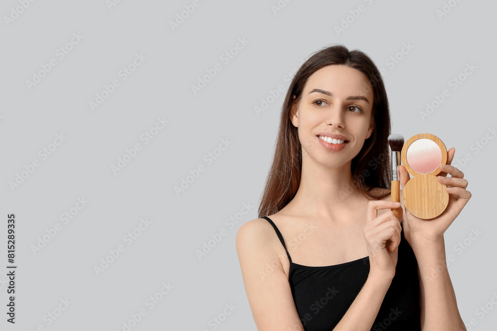 Beautiful young woman holding brush and highlighter on white background