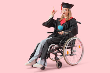 Wall Mural - Shocked female graduate in wheelchair with globe pointing at something on pink background