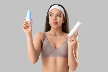 Poster - Thoughtful young woman with deodorants on light background