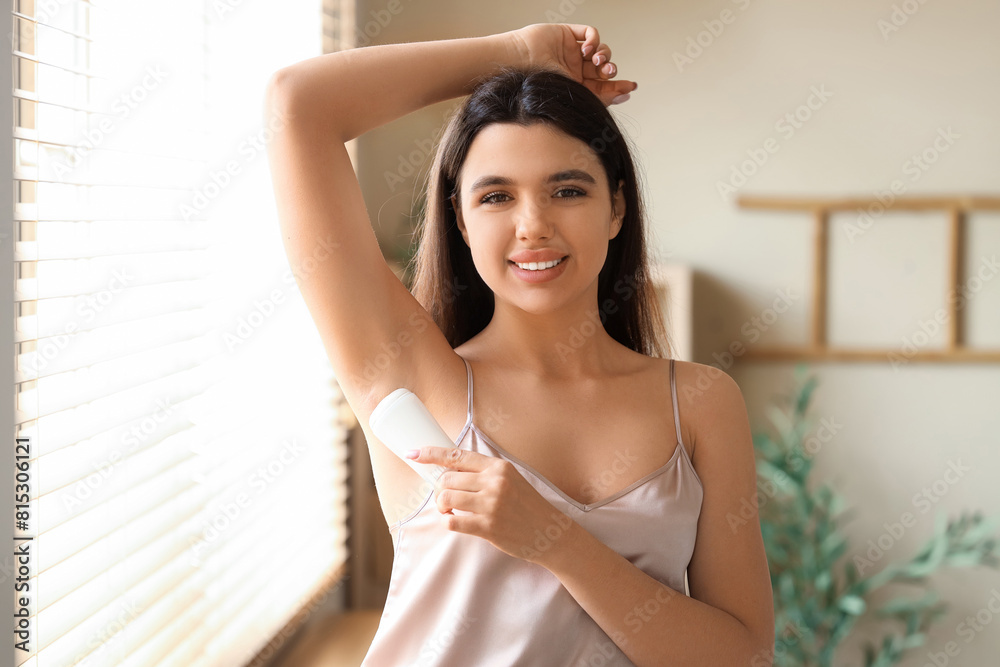 Young woman applying deodorant at home