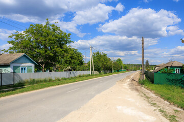 Wall Mural - A rural road with a few houses and trees in the background