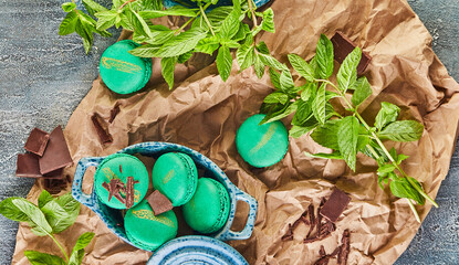 Canvas Print - Green macarons topped with chocolate and mint leaves on a table