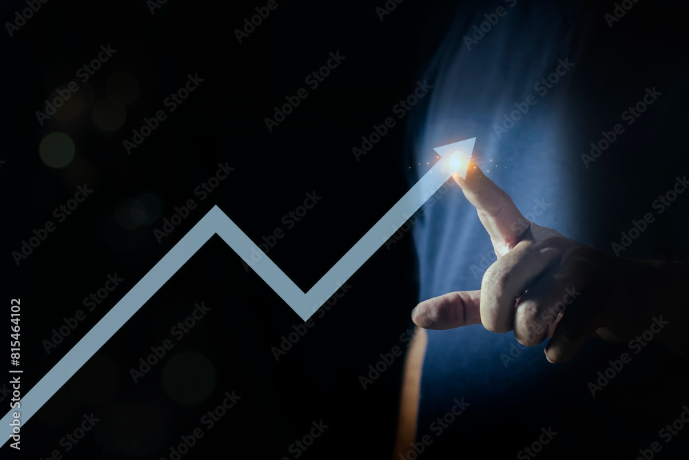 Man hand pointing arrow with glowing graph line on a dark blue ...