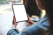 © Farknot Architect - Mockup image of a woman holding digital tablet with blank white desktop screen in cafe