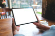 © Farknot Architect - Mockup image of a woman holding digital tablet with blank white desktop screen in cafe