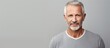 © HN Works - Confident mature man wearing a shirt standing against a grey background looking at the camera and pointing towards copy space image
