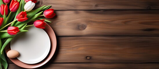 Wall Mural - Top down view of a beautifully arranged wooden background adorned with a white plate cutlery tulips and Easter eggs Ample copy space provided