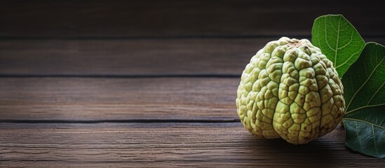 Poster - A ripe cherimoya fruit placed on a wooden table with a top down view The image has copy space and a horizontal aspect