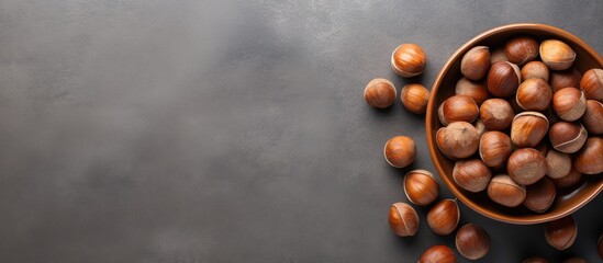 Aufkleber - Top view of a bowl filled with hazelnuts on a grey background providing copy space for the image