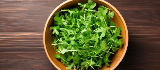 Aufkleber - A top down view of a wooden background featuring a bowl of fresh rucola salad with available copy space