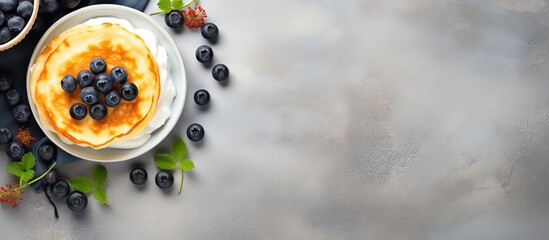 Poster - Top view of a copy space image featuring light background with cottage cheese pancakes sour cream and blueberries Suitable for breakfast or lunch