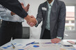 © crizzystudio - Young businessman and financial representative shaking hands after a budget deal for business expansion and investment in a village construction project real estate financial concept.